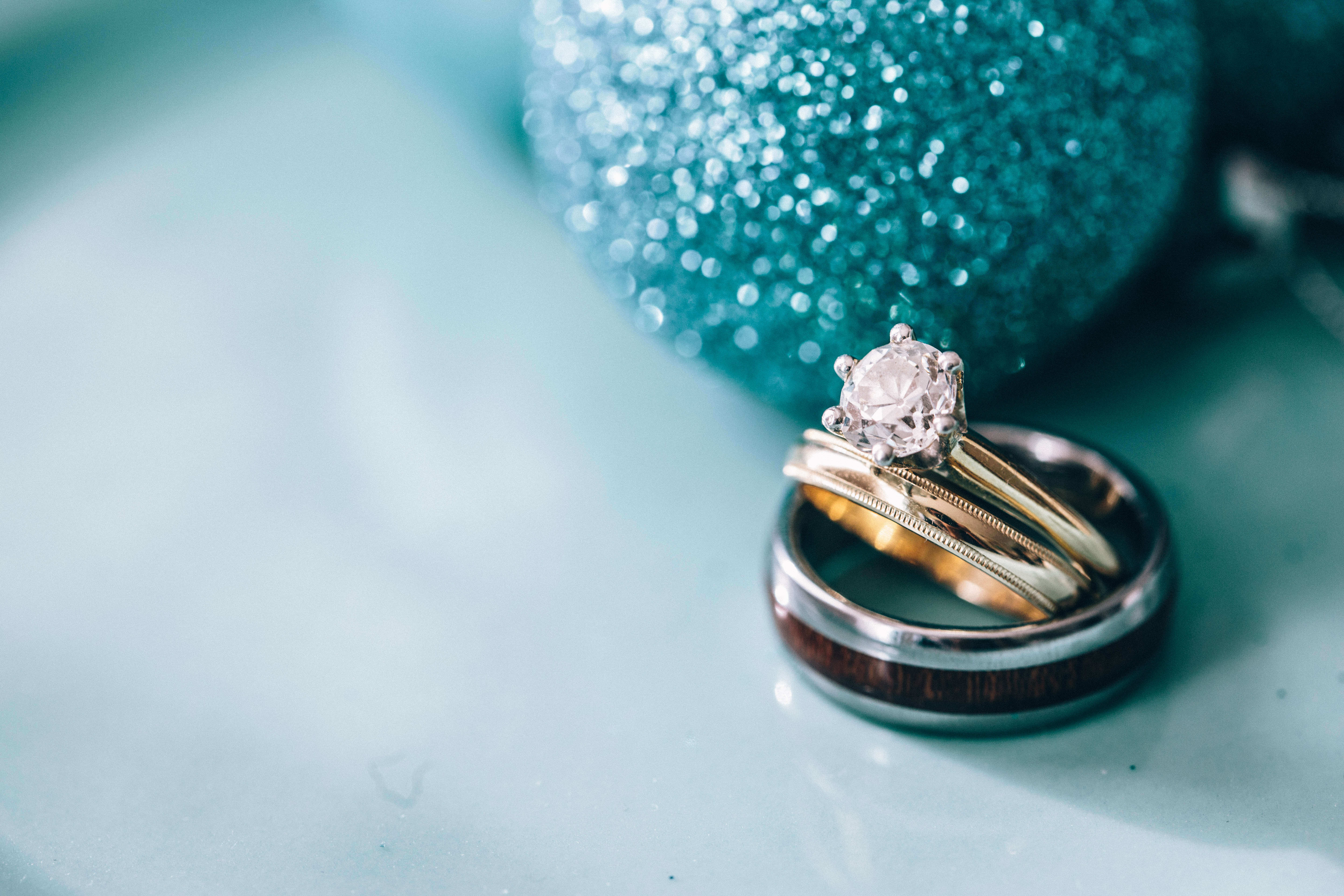 Round princess cut engagement ring and wedding rings next to glitter Christmas ornaments