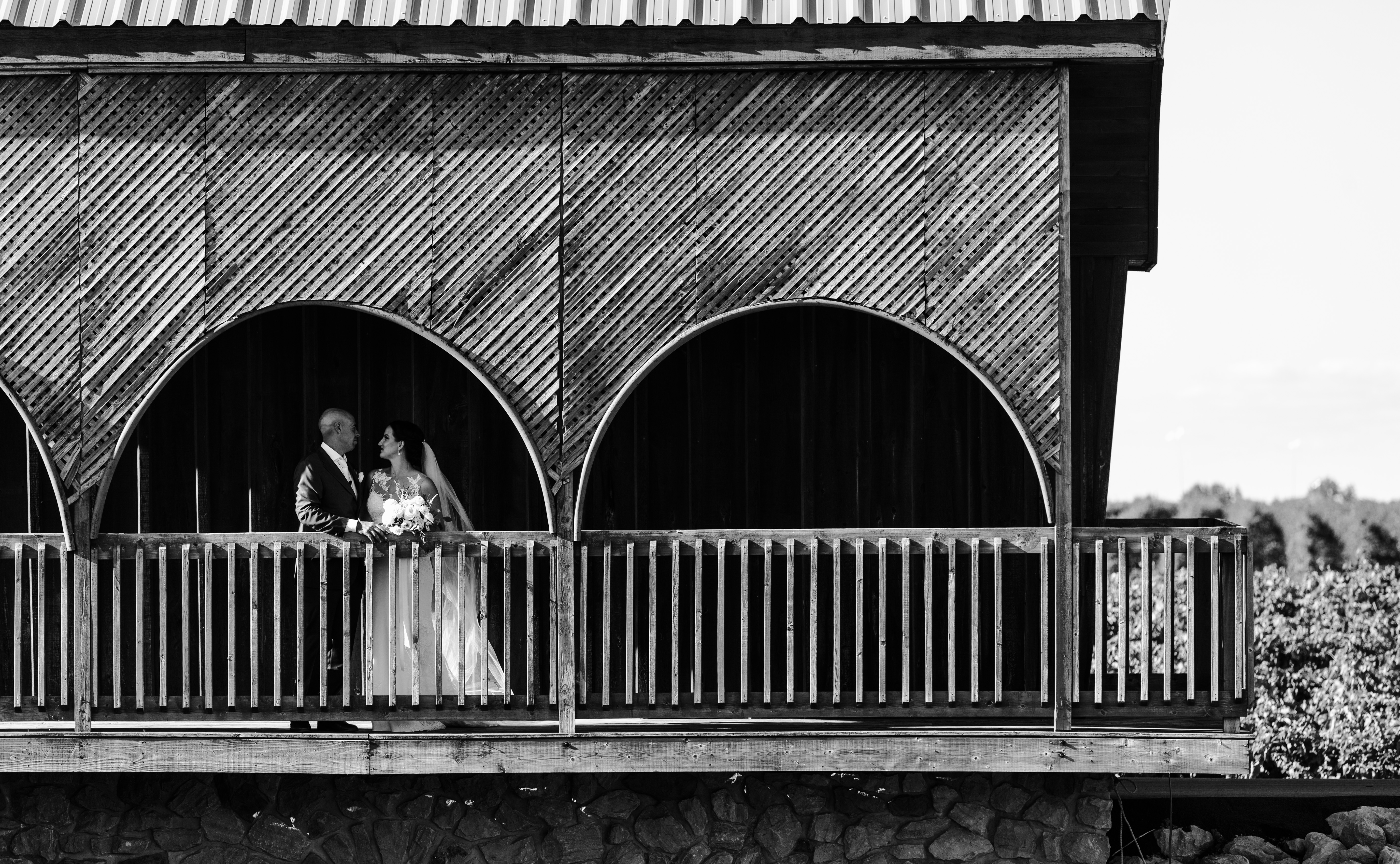 Bride and groom stand side by side on the covered bridge at Hernder Estate during their summer vineyard wedding in Niagara