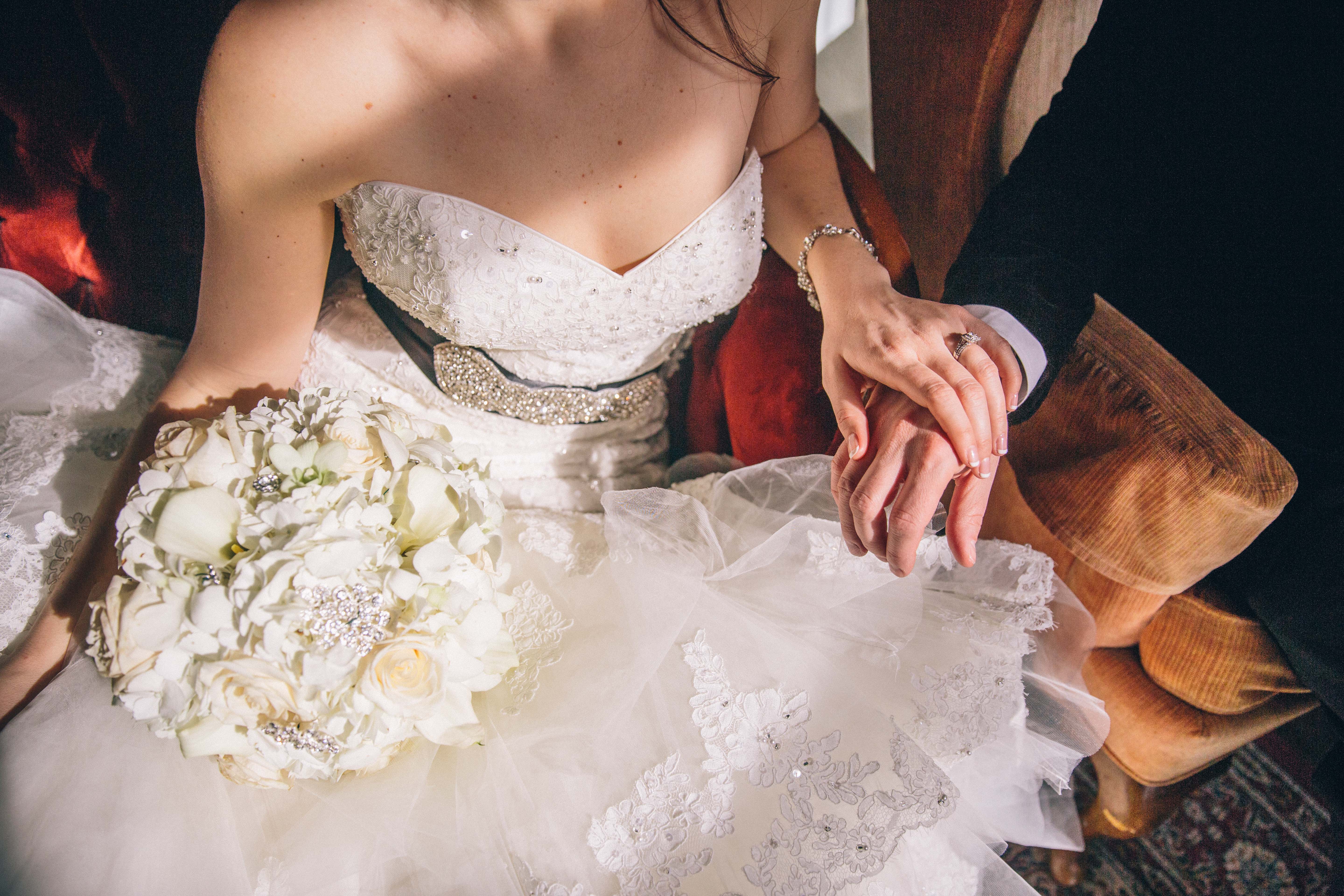 Bride holding groom's hand in a slant of light