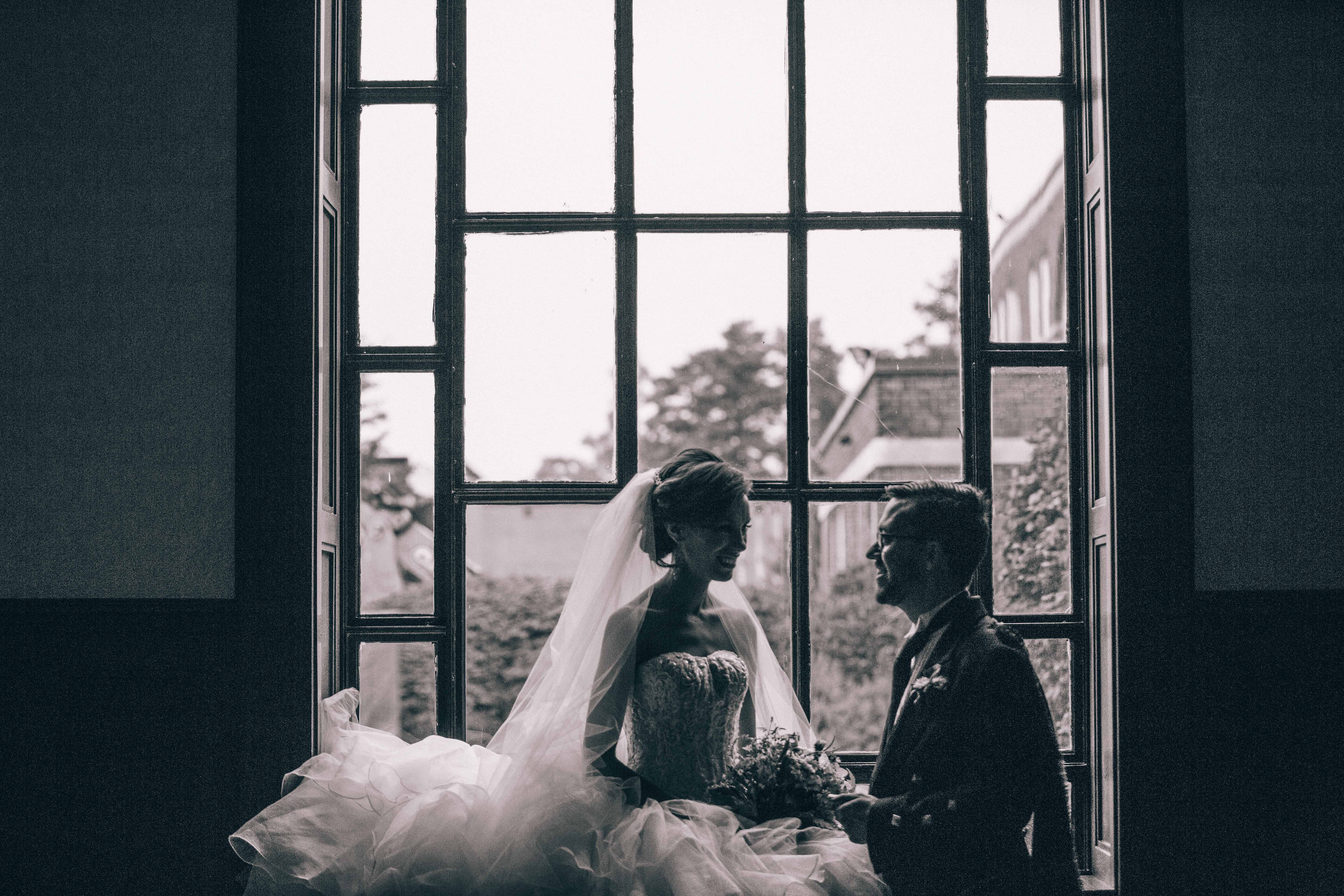 A bride and groom sit in the windows at St. Andrew's College in Aurora Ontario during their summer wedding in Toronto